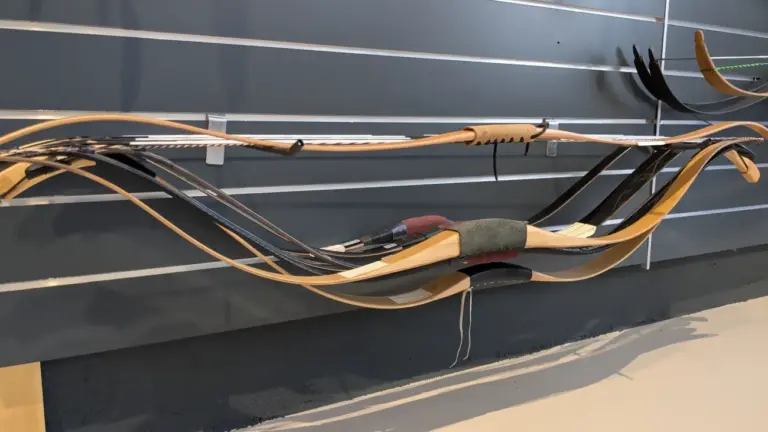 Mehrere Reiterbögen hängen gespannt an einer Wand.