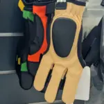 Verschiedene Schießhandschuhe aus Leder hängen an einer Wand.